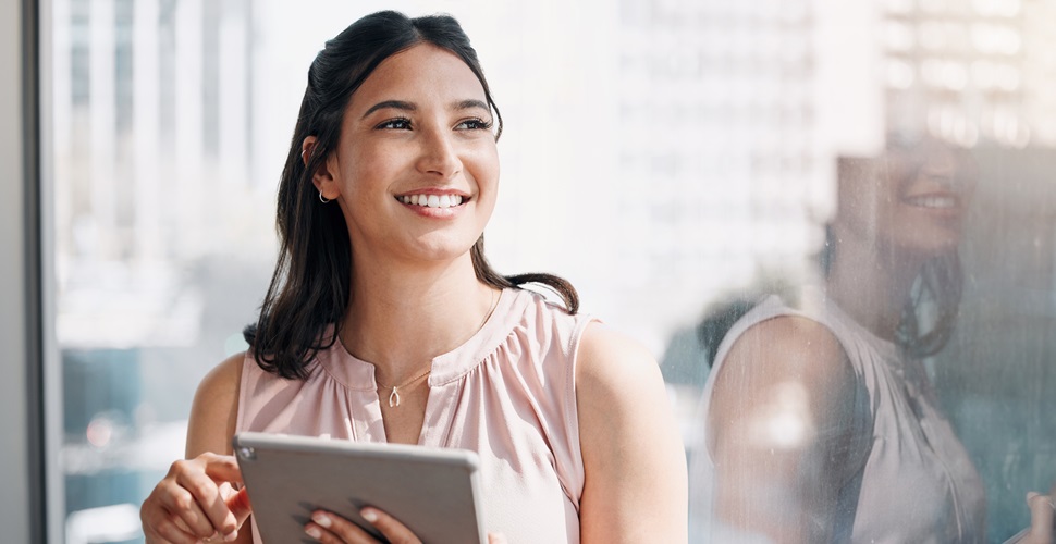 A woman looking positive into the distance while holding a tablet.