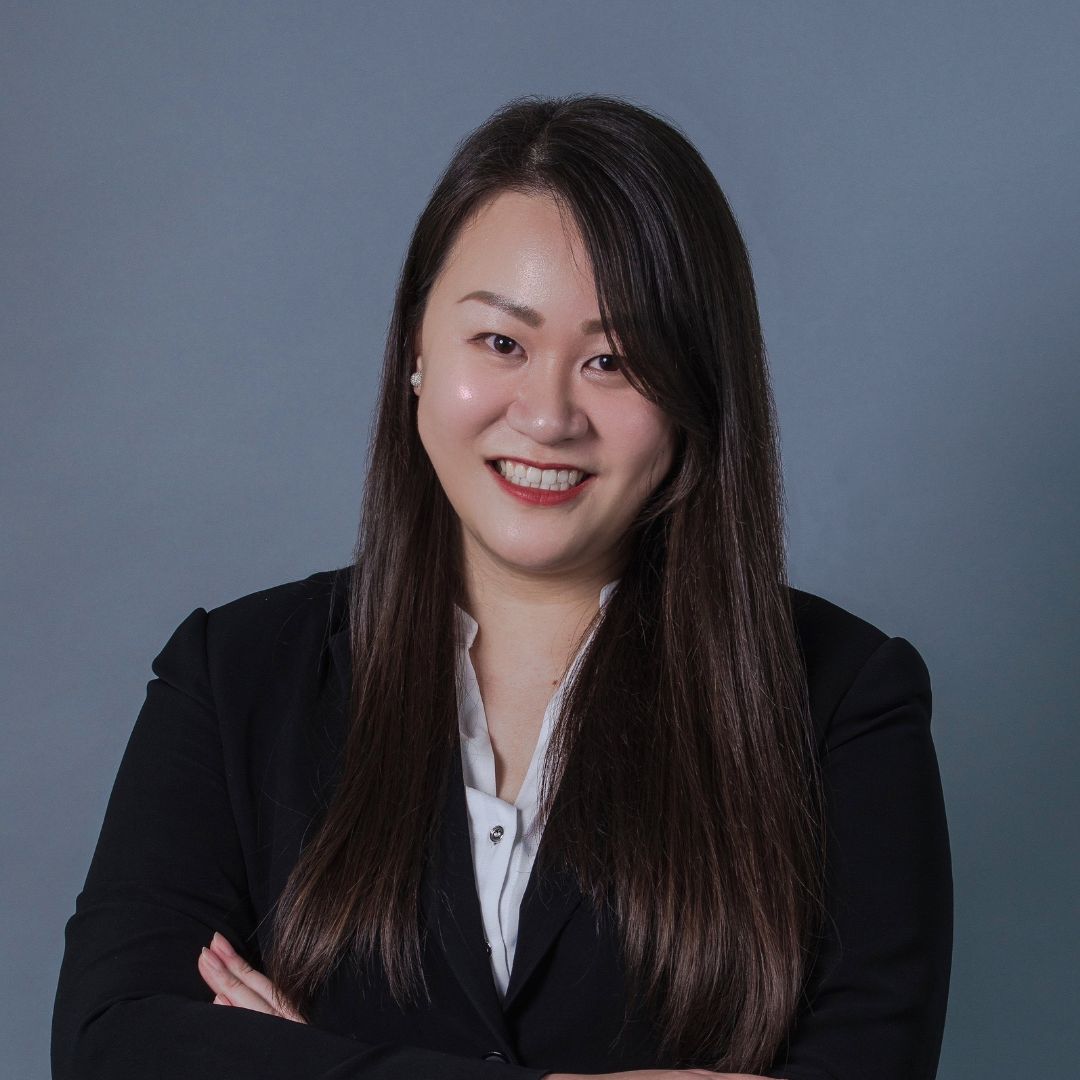 Person in a black blazer smiling with arms crossed.