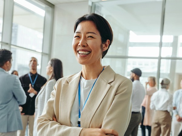 A lady in an office attire smiling with a blue gradient background.
