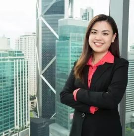 Smiling woman in a black blazer with cityscape background.