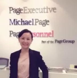 Woman in business attire standing in front of PageGroup branding at an office reception desk.