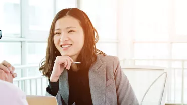 Woman smiling during a meeting in a sunlit office.