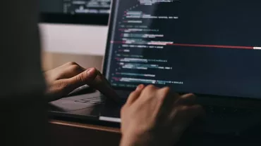 Hands typing code on a laptop keyboard.
