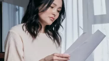 Woman reading a document in a softly lit room.