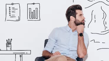 Man sitting in front of wall with doodles of office space and mountains.