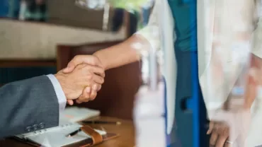 Two people shaking hands in a business setting.