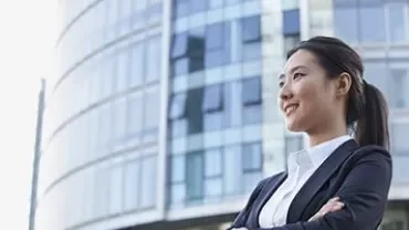 Confident businesswoman in a suit standing in front of a modern glass building.