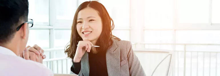 Woman smiling during a meeting in a sunlit office.