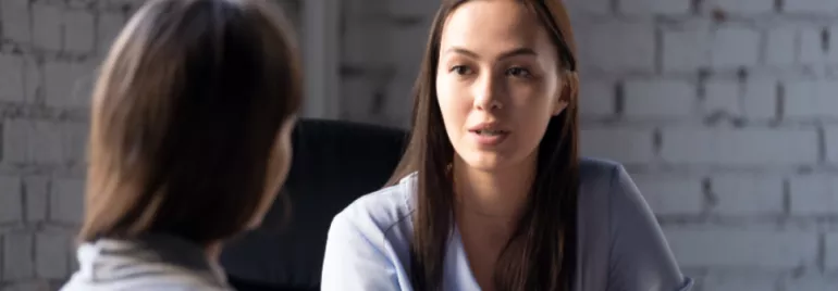 Two women having a conversation in an office setting.
