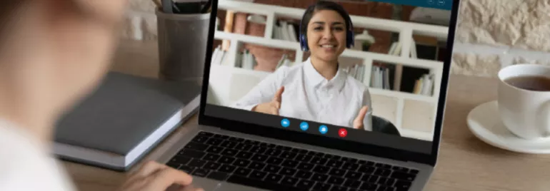 An employee having a video call facing a laptop with the video on