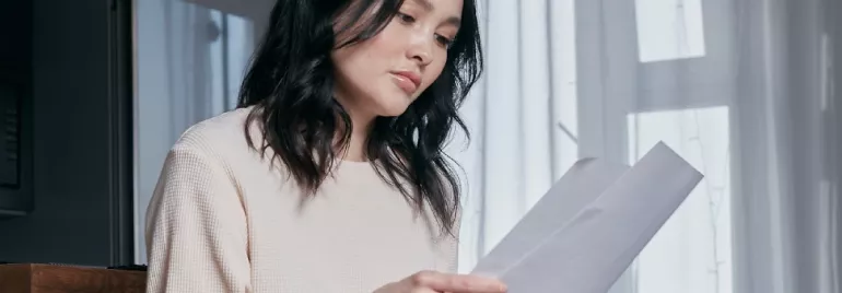 Woman reading a document in a softly lit room.