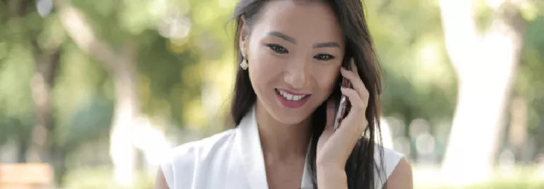 Woman smiling and talking on the phone outdoors.