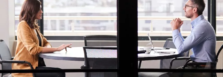 Two professionals having a discussion at a round table in an office setting.