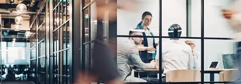 Business meeting in a modern glass-walled office room.