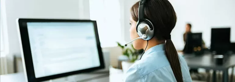 Woman with headset working at a computer in an office setting.