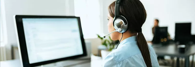 Woman with headset working at a computer in an office setting.