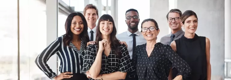 A diverse group of professionals smiling in a bright office setting.