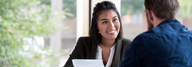 Woman smiling during a meeting, holding a document.