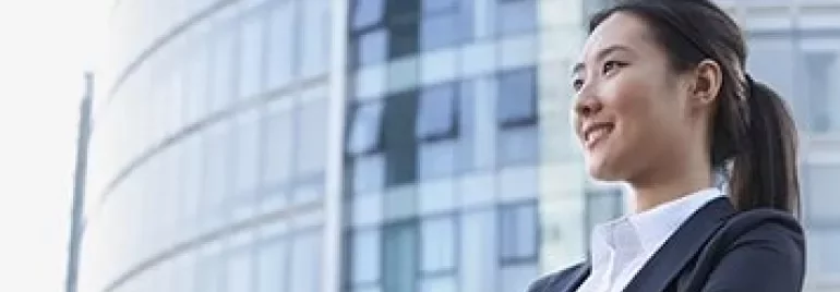 Confident businesswoman in a suit standing in front of a modern glass building.