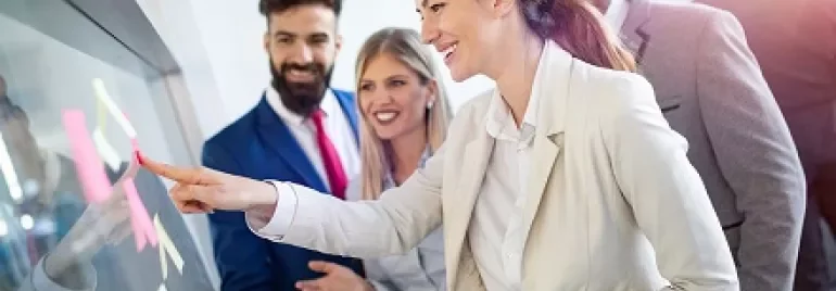 Team collaborating at an office meeting with sticky notes on a glass board.