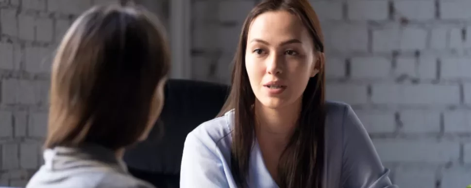 Two women having a conversation in an office setting.