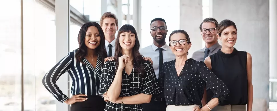A diverse group of professionals smiling in a bright office setting.