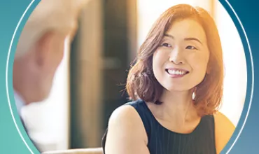 Smiling woman in conversation, wearing a black dress.