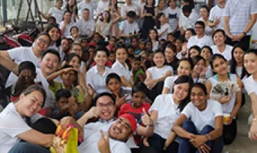 A large group of people posing together indoors, many wearing white shirts.
