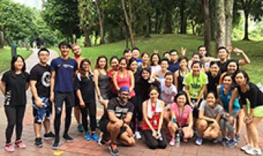 A group of people posing outdoors on a paved path surrounded by trees.
