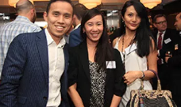 Three people smiling at a networking event.
