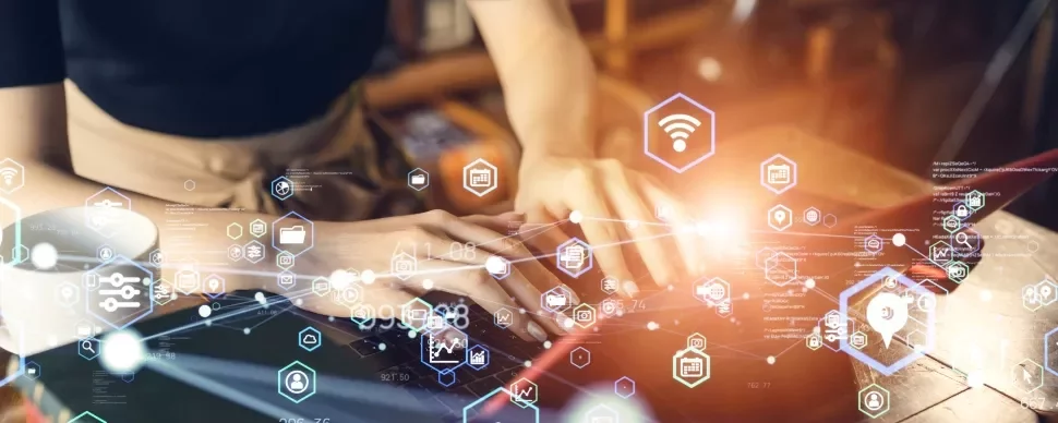 Person typing on laptop with digital icons floating around.