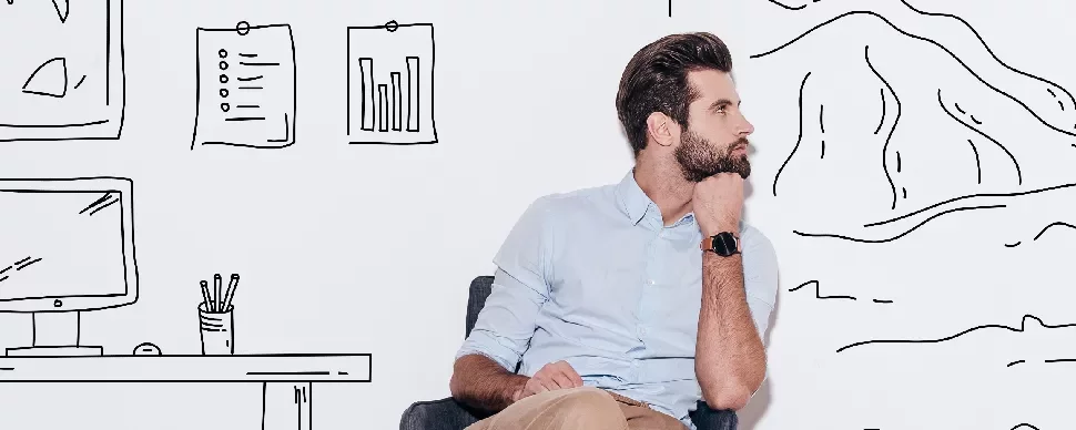 Man sitting in front of wall with doodles of office space and mountains.