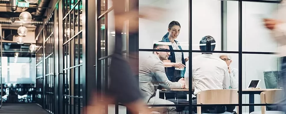 Business meeting in a modern glass-walled office room.