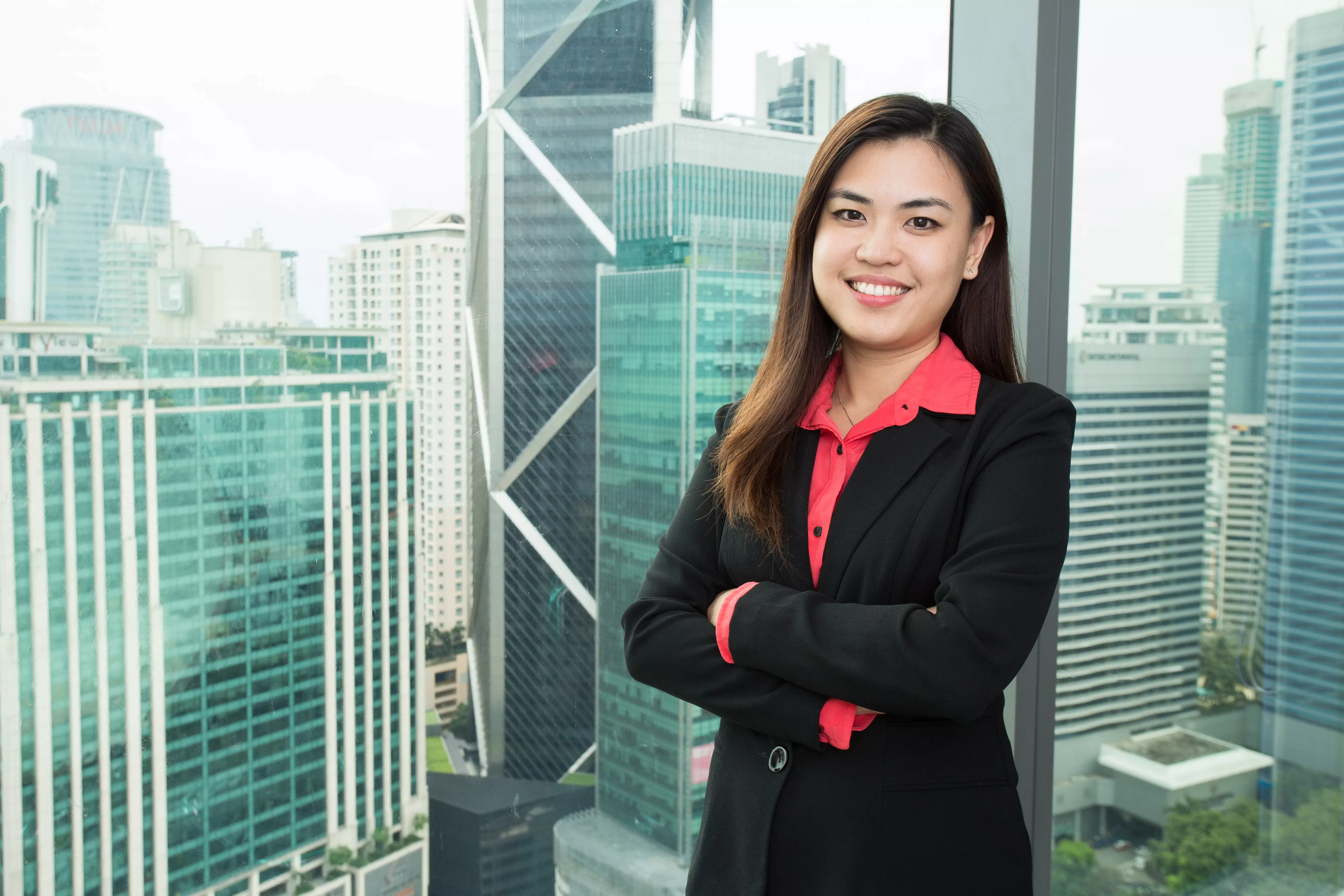Smiling woman in a black blazer with cityscape background.