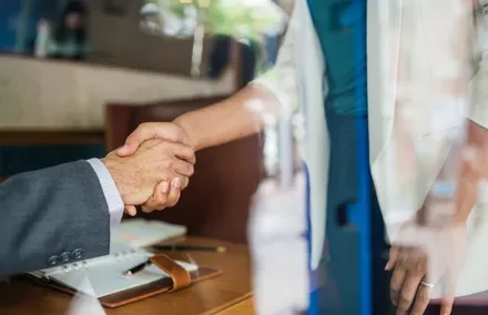 Two people shaking hands in a business setting.