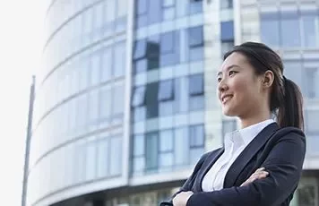 Confident businesswoman in a suit standing in front of a modern glass building.