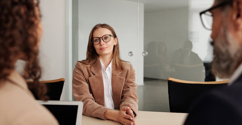 Woman in Brown Blazer seated beside Table